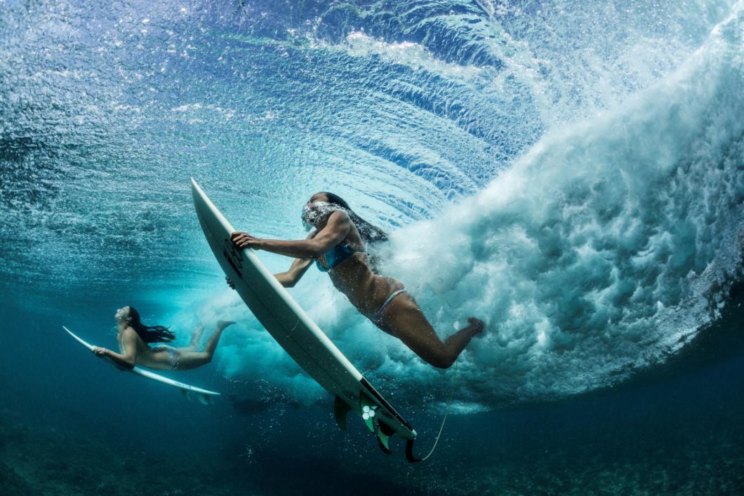 Deskarja pod valom, katerega mogočni sili sta se izmaknila, usmerjata vsak svojo desko nazaj proti mirnejši gladini Tihega oceana ob legendarni obali pri mestu Makaha.  FOTOGRAFIJA: PAUL NICKLEN; OAHU, HAVAJI