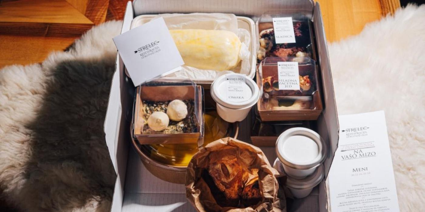 Slika kulinaričnega paketa iz restavracije Strelec v dostavni škatli.